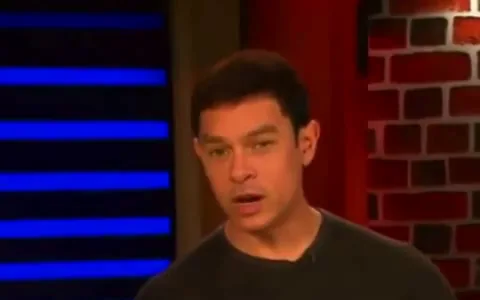 A frame from a video of a man talking in a studio, with a box drawn around his face.